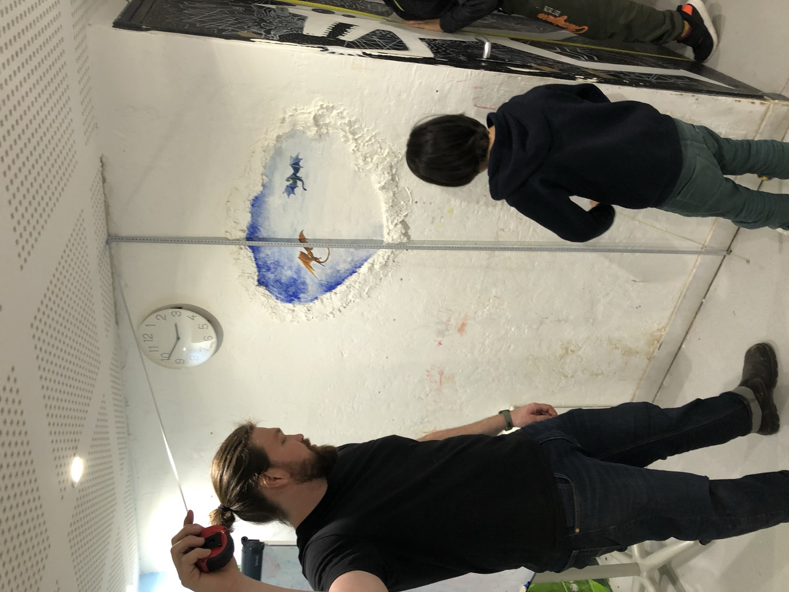 Un intervenant et un enfant devant une fresque en cours