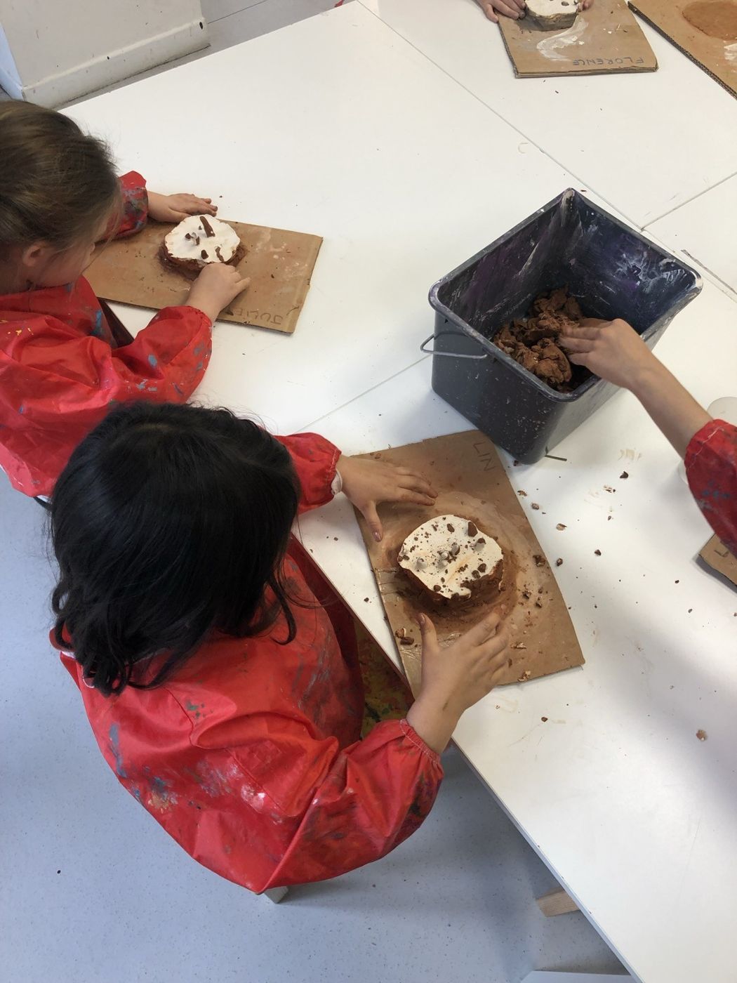 Des enfants travaillent l'argile en tablier