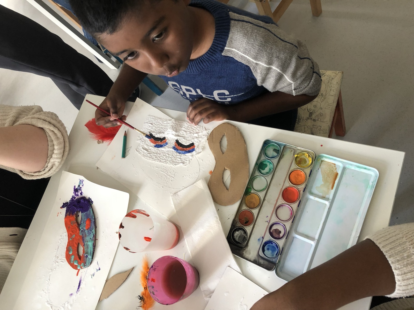 Des godets de peinture et des pinceaux autour d'une enfant