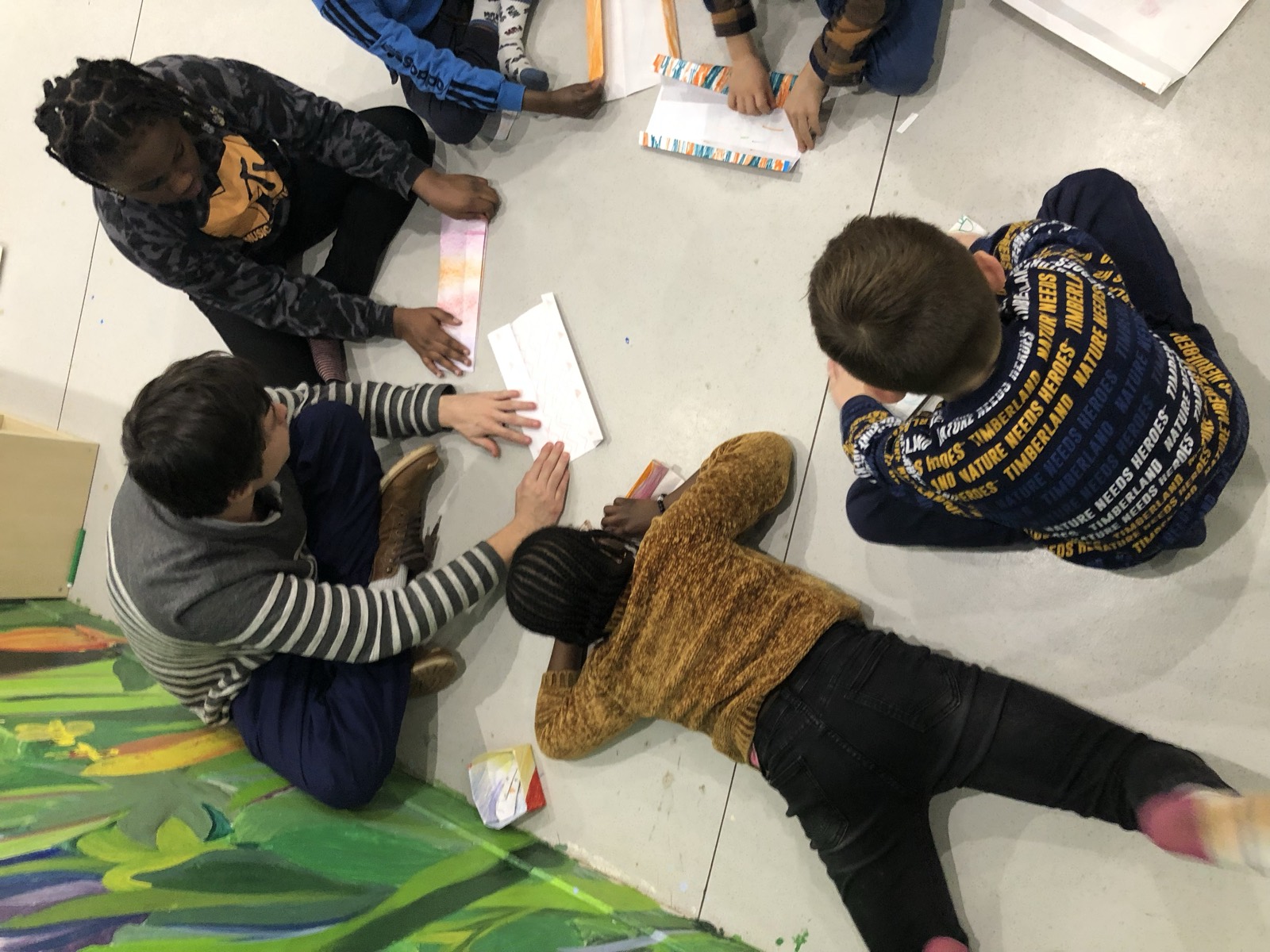 Des enfants dessinent allongés au sol
