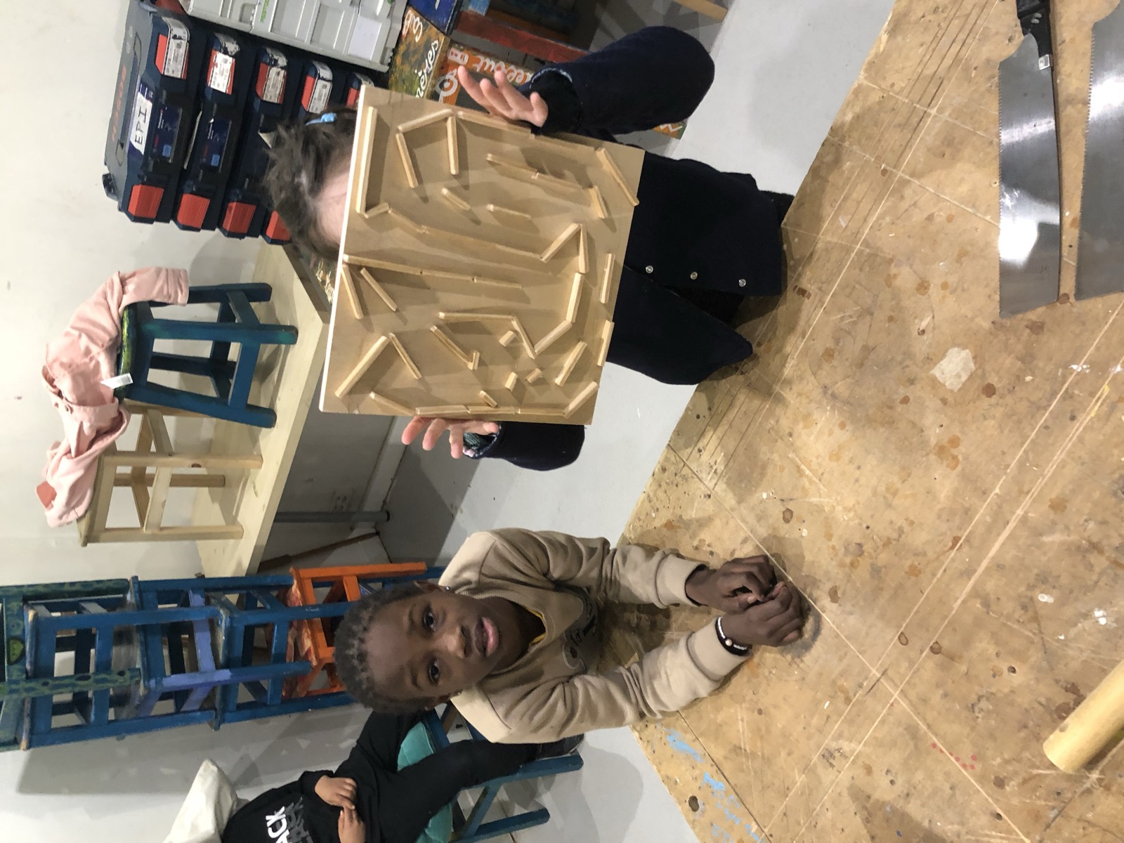 Un enfant montre la plaque de bois qu'il a gravée