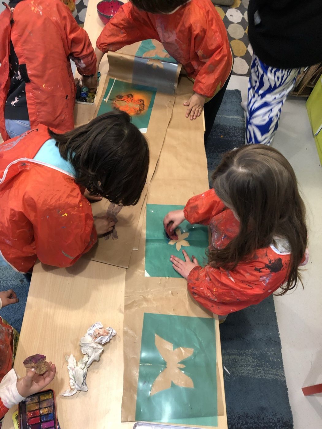 Des enfants impriment des motifs à travers des pochoirs